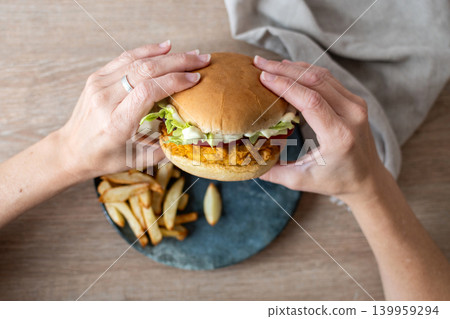 Woman holding crispy chicken burger Woman holding crispy chicken burger 139959294