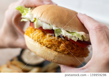 Woman holding crispy chicken burger Woman holding crispy chicken burger 139959296