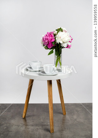 bouquet of peonies and two coffee cups on a modern round side table. An element of interior design. 139959558
