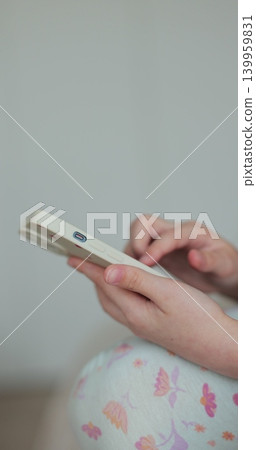 Vertical video. Close-up hand of girl using smartphone in the living room at home, typing message. Vertical video. Close-up hand of girl using smartphone in the living room at home, typing message. 139959831