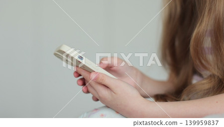 Close up little child girl using mobile phone at home. Daughter scrolling smartphone technology watching funny video in social media. The problem of addiction to gadgets. Close up little child girl using mobile phone at home. Daughter scrolling smartphone technology watching funny video in social media. The problem of addiction to gadgets. 139959837