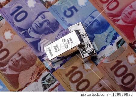 A silver bar, white metal against a backdrop of Canadian money, as a concept. A silver bar A silver bar, white metal against a backdrop of Canadian money, as a concept. A silver bar 139959953