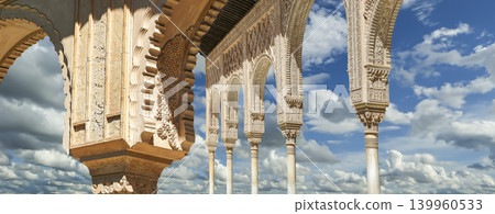 Arches in Islamic (Moorish) style (against the background of a beautiful sky with clouds) in Alhambra, Granada, Spain Arches in Islamic (Moorish) style (against the background of a beautiful sky with clouds) in Alhambra, Granada, Spain 139960533