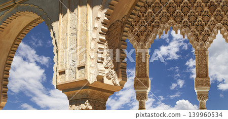 Arches in Islamic (Moorish) style (against the background of a beautiful sky with clouds) in Alhambra, Granada, Spain Arches in Islamic (Moorish) style (against the background of a beautiful sky with clouds) in Alhambra, Granada, Spain 139960534