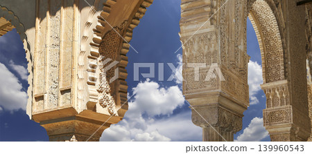 Arches in Islamic (Moorish) style (against the background of a beautiful sky with clouds) in Alhambra, Granada, Spain Arches in Islamic (Moorish) style (against the background of a beautiful sky with clouds) in Alhambra, Granada, Spain 139960543