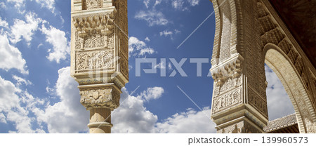 Arches in Islamic (Moorish) style (against the background of a beautiful sky with clouds) in Alhambra, Granada, Spain Arches in Islamic (Moorish) style (against the background of a beautiful sky with clouds) in Alhambra, Granada, Spain 139960573
