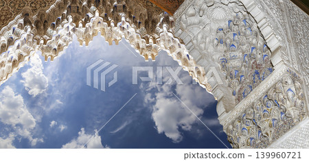 Arches in Islamic (Moorish) style (against the background of a beautiful sky with clouds) in Alhambra, Granada, Spain Arches in Islamic (Moorish) style (against the background of a beautiful sky with clouds) in Alhambra, Granada, Spain 139960721