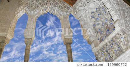 Arches in Islamic (Moorish) style (against the background of a beautiful sky with clouds) in Alhambra, Granada, Spain Arches in Islamic (Moorish) style (against the background of a beautiful sky with clouds) in Alhambra, Granada, Spain 139960722