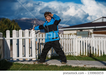 Boy in the yard of a country house looks into the distance and smiles 139960859