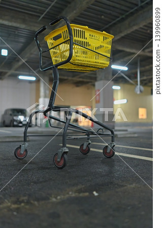 A yellow shopping cart placed in an indoor parking lot 139960899
