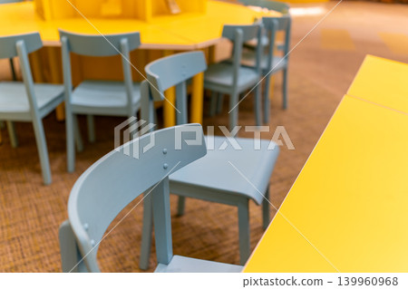 A colorful interior space with a yellow table and light blue chairs. A colorful interior space with a yellow table and light blue chairs. 139960968