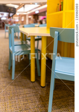 A colorful interior space with a yellow table and light blue chairs. A colorful interior space with a yellow table and light blue chairs. 139960969