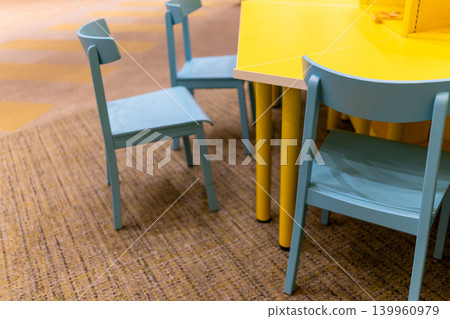 A colorful interior space with a yellow table and light blue chairs. A colorful interior space with a yellow table and light blue chairs. 139960979
