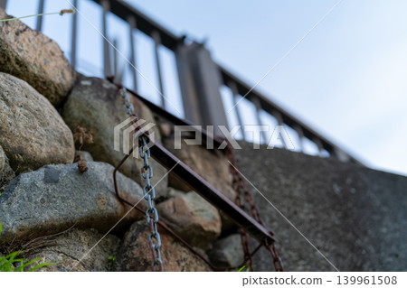 A rusty metal chain ladder hanging on a stone wall 139961508