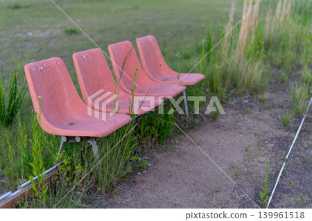 An orange bench left in a vacant lot covered with grass. An orange bench left in a vacant lot covered with grass. 139961518