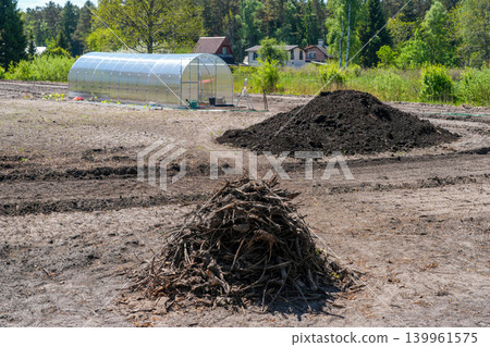 Land clearing and greenhouse setup on rural farm plot during agricultural site preparation 139961575