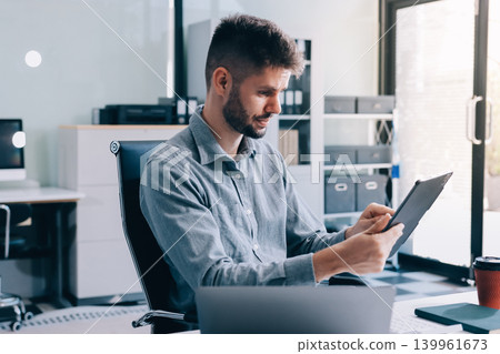 Tired worker. A tired businessman works in the evening. A man in office clothes is holding his temples. Problems in business. The businessman is trying to solve the problems that have arisen. 139961673