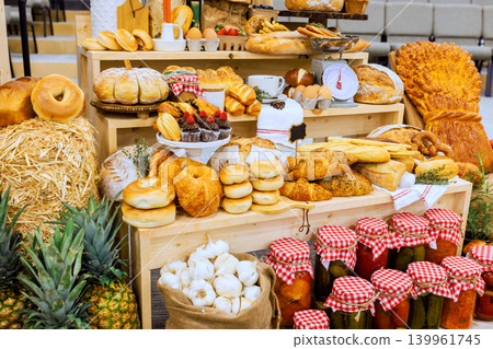 There is large table full of baked items jars of pickles at farm rural market event many foods are neatly arranged. There is large table full of baked items jars of pickles at farm rural market event many foods are neatly arranged. 139961745