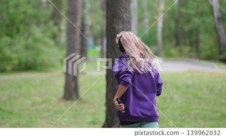 Portrait of young sportswoman jogging during outdoor training in park in the morning. Sport and healthy lifestyle concept Portrait of young sportswoman jogging during outdoor training in park in the morning. Sport and healthy lifestyle concept 139962032