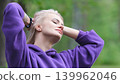 Blonde in purple sweatshirt doing morning exercises, breathing fresh air in forest 139962046