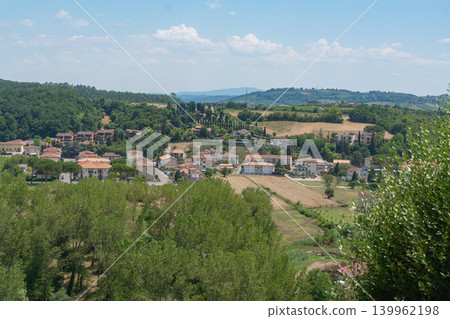 Lush green hills with village houses under bright sky. Perfect for travel brochures, countryside lifestyle branding and peaceful vacation themes Certaldo, Italy. 139962198