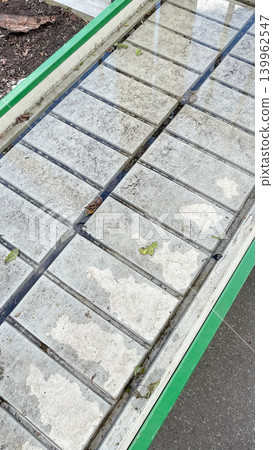 An empty greenhouse ebb and flow irrigation table with concrete slabs and drainage channels on display at a garden center An empty greenhouse ebb and flow irrigation table with concrete slabs and drainage channels on display at a garden center 139962547