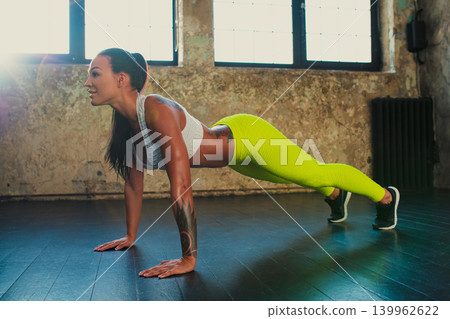 Young slim fitness woman doing push-ups, tattoo on body Young slim fitness woman doing push-ups, tattoo on body 139962622