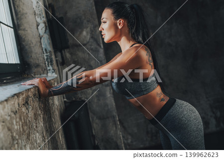 Young slim sexy fitness woman looking out the window, tattoo on body Young slim sexy fitness woman looking out the window, tattoo on body 139962623