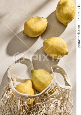 Fresh Italian Lemons in an Eco-Friendly Mesh Bag on a Linen Tablecloth. Top View 139962710
