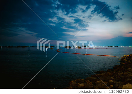 A scene of fishing boats lined up on the night sea and red oil fences. A scene of fishing boats lined up on the night sea and red oil fences. 139962780