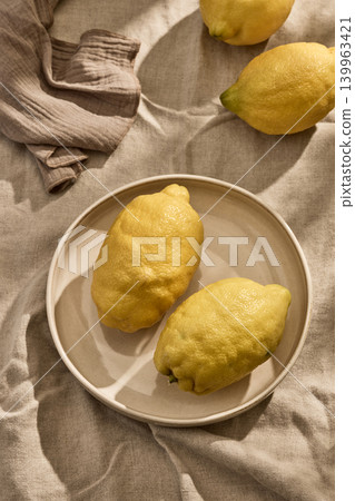 Fresh Italian Lemons on a Ceramic Plate on a Linen Tablecloth in Warm Tones. Top View Fresh Italian Lemons on a Ceramic Plate on a Linen Tablecloth in Warm Tones. Top View 139963421