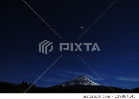 在皎潔的月光下，富士山在夜空中熠熠生輝，山谷中殘留的積雪被風吹散，形成一道道耀眼的垂直條紋，構成了一幅令人嘆為觀止的景象。 139964145