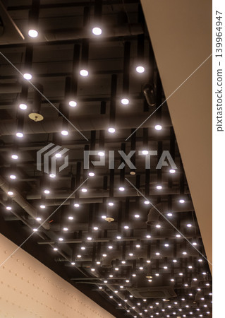 Modern ceiling design featuring integrated lights on exposed black tubes in a contemporary interior space. Modern ceiling design featuring integrated lights on exposed black tubes in a contemporary interior space. 139964947