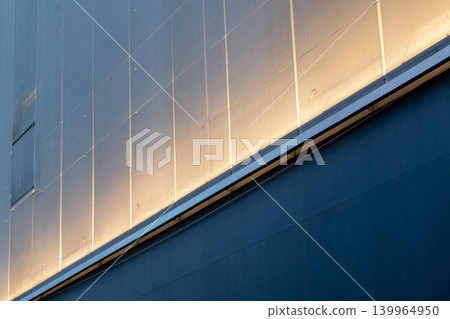 Continuous linear uplighting illuminating the facade of a building, highlighting architectural lines and surface textures at night. Continuous linear uplighting illuminating the facade of a building, highlighting architectural lines and surface textures at night. 139964950