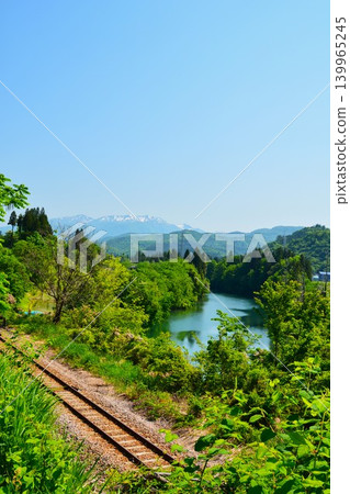 The single-track Tadami Line runs along the Hagamagawa River in Sumon, Uonuma City, amidst the fresh greenery of spring. The single-track Tadami Line runs along the Hagamagawa River in Sumon, Uonuma City, amidst the fresh greenery of spring. 139965245