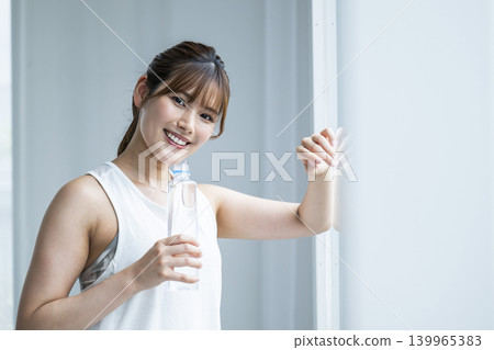 Young woman, wearing sportswear, looking at the camera, hydrating. Young woman, wearing sportswear, looking at the camera, hydrating. 139965383