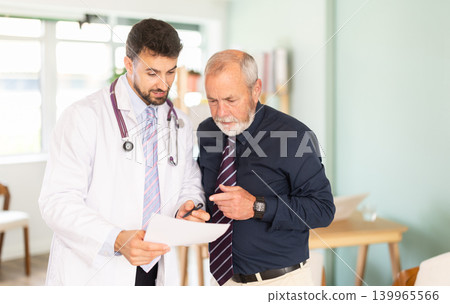 Adult doctor discussing medical tests with elderly male patient Adult doctor discussing medical tests with elderly male patient 139965566