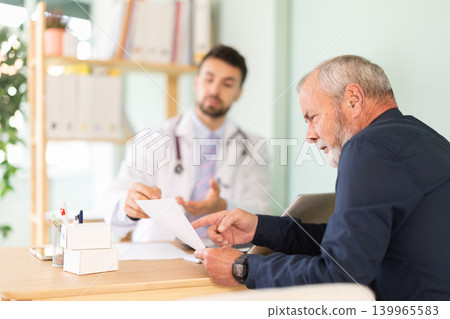Male doctor and mature man patient examine papers, discuss medical tests result. 139965583