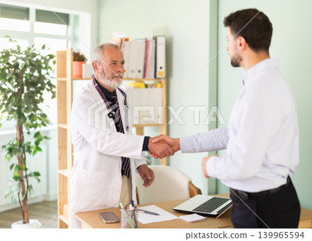Successful medical appointment, senior male doctor and man patient shake hands. Successful medical appointment, senior male doctor and man patient shake hands. 139965594