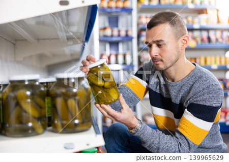Adult man chooses pickled cucumbers in store Adult man chooses pickled cucumbers in store 139965629