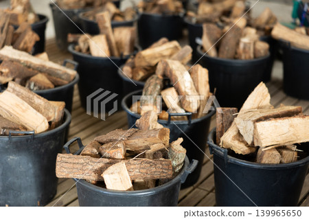 Firewood stacked in plastic buckets in store warehouse 139965650