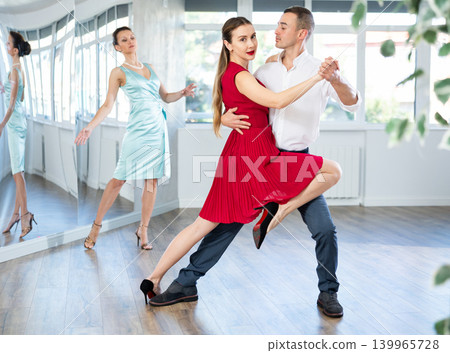 Graceful duet dancing passionate tango during dance class Graceful duet dancing passionate tango during dance class 139965728