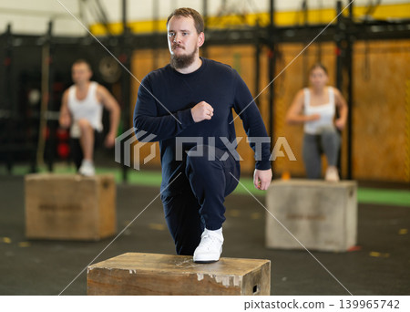 Young bearded man stepping up onto box during cross training Young bearded man stepping up onto box during cross training 139965742