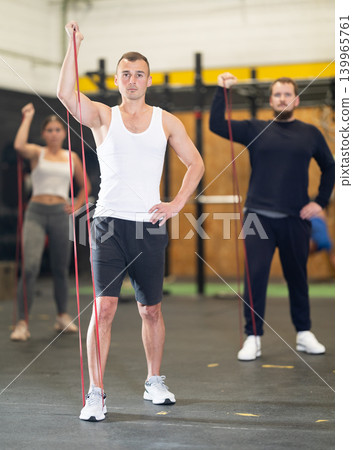 Determined young guy working out with resistance band in gym 139965761