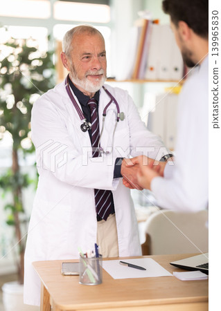 Successful medical appointment, senior male doctor and man patient shake hands. Successful medical appointment, senior male doctor and man patient shake hands. 139965830