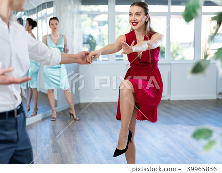Couple in stage costumes learns boogie woogie dancing during individual lesson Couple in stage costumes learns boogie woogie dancing during individual lesson 139965836