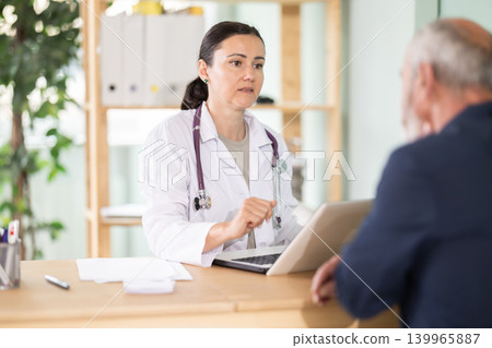 Female doctor listens attentively to a elderly patient complaints in clinic 139965887