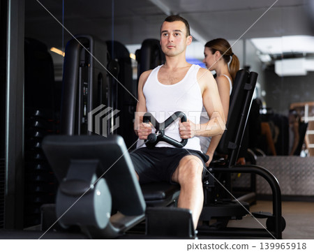 Man pulls handle of simulator with effort during strength training. Man pulls handle of simulator with effort during strength training. 139965918