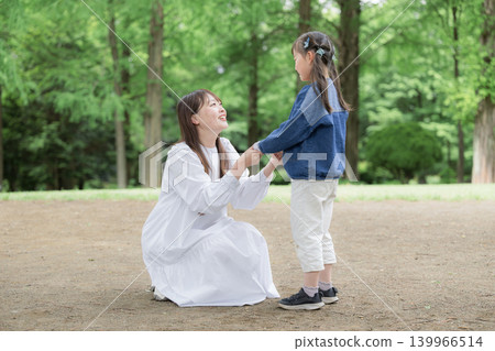 An image of a parent-child lifestyle: smiling, holding hands, gazing into each other's eyes, and touching each other amidst the fresh greenery of nature. An image of a parent-child lifestyle: smiling, holding hands, gazing into each other's eyes, and touching each other amidst the fresh greenery of nature. 139966514