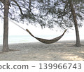 A bamboo hammock hangs under a pine tree on the beach by the sea. 139966743